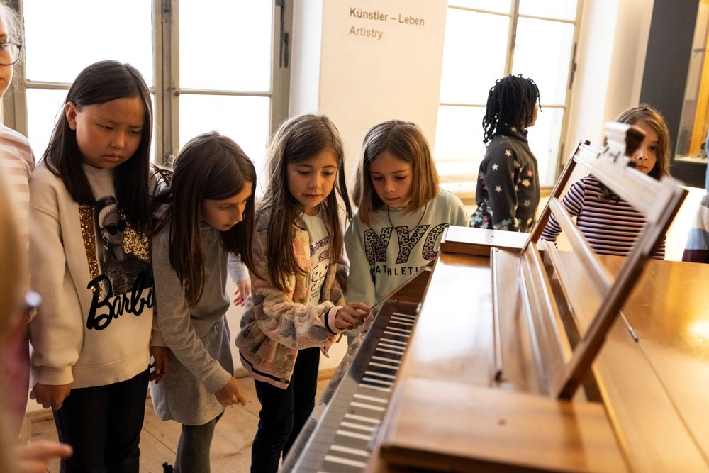 Das klingende Museum: Kids standing around a piano